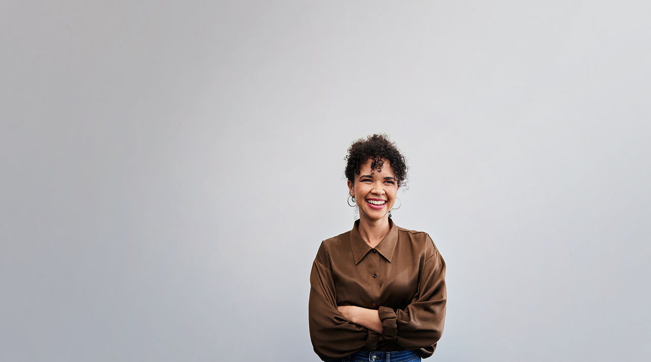 An Asian woman in a contemporary interior holds and looks intently at a tablet computer.