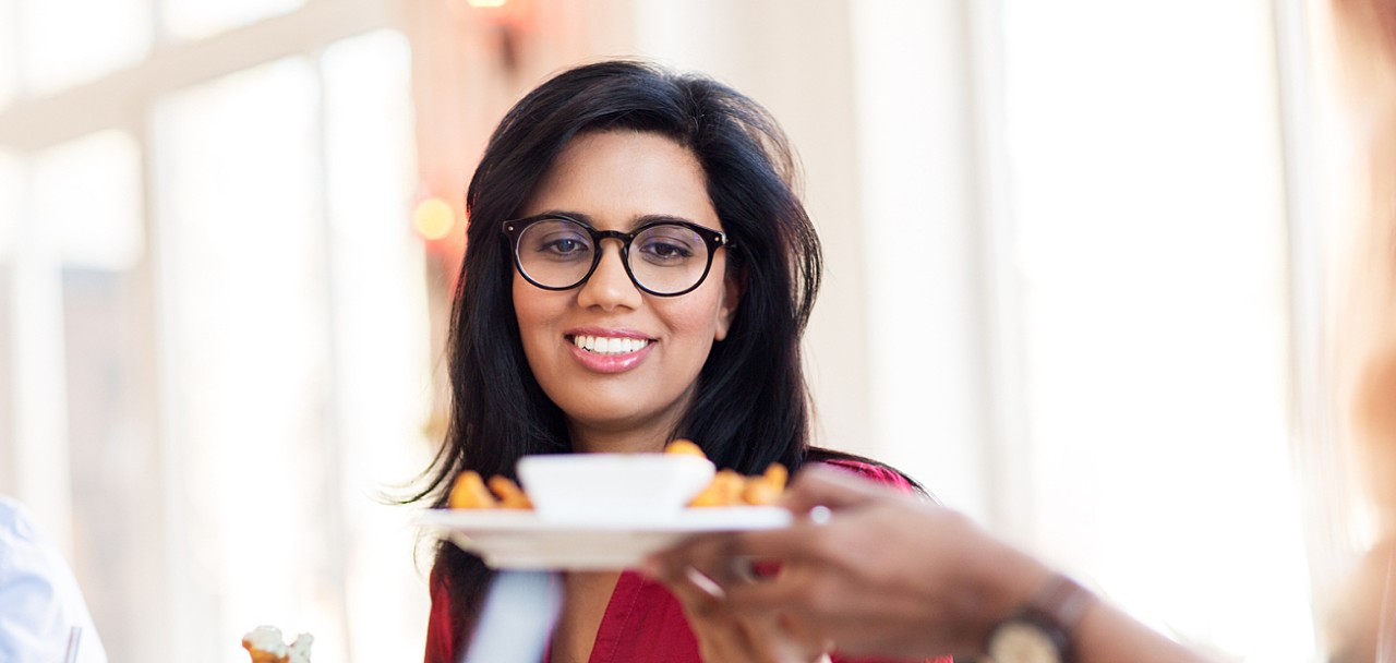 leisure, food and people concept - happy indian woman with friends eating at restaurant