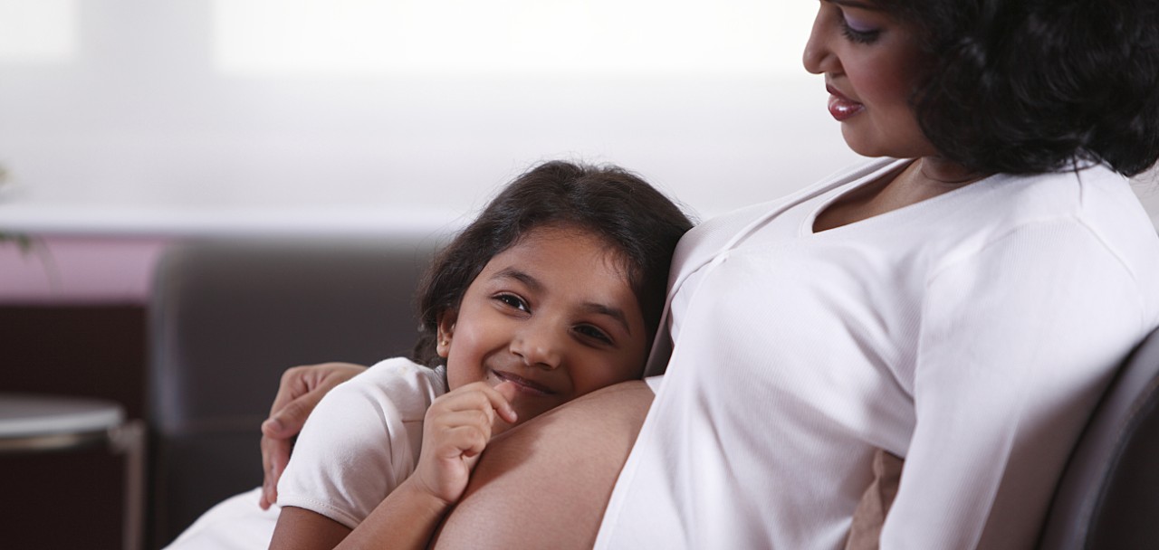 Young girl with ear up to mothers pregnant belly; Shutterstock ID 669356410; PO: 123