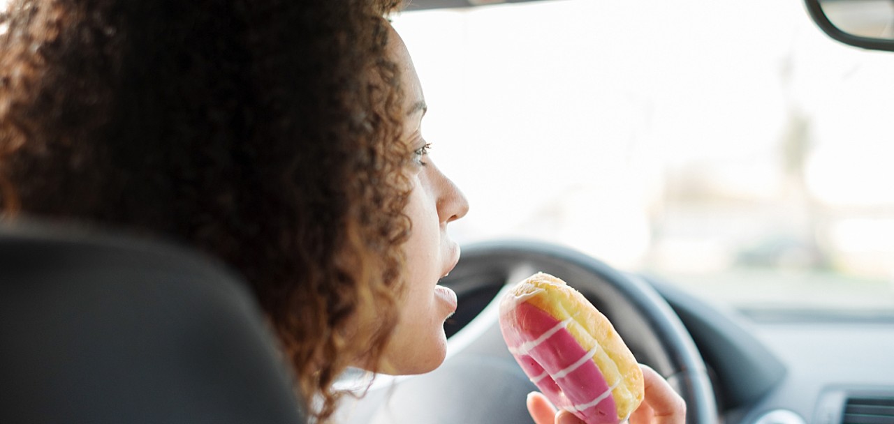 Woman eating a sweet driving her car