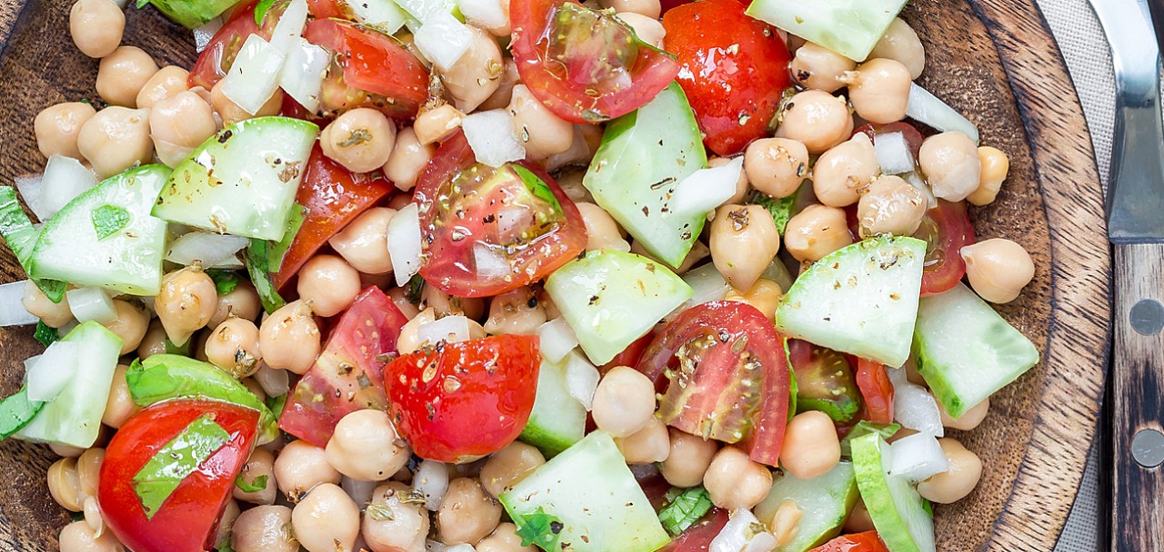 Chickpeas salad with cherry tomatoes cucumbers basil and onion with citrus dressing top view square format