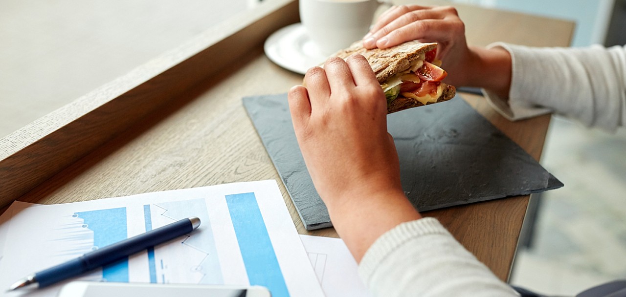 business, food and people concept - woman with papers eating salmon panini sandwich at cafe for dinn