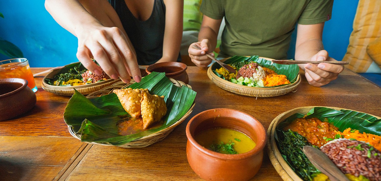 Vegetarian Indian food. several people eat Indian food at a common table together.